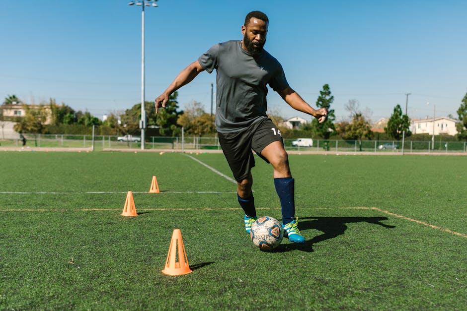 youth soccer drills for beginners - Adult soccer player warming up with cones on a sunny day.