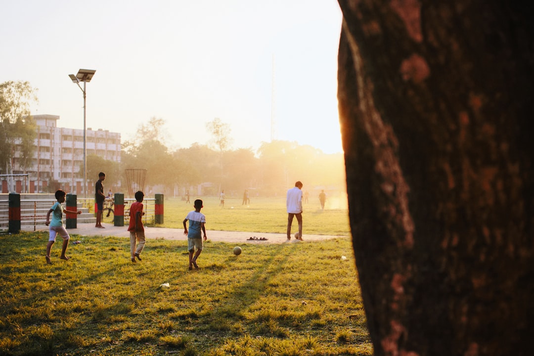 soccer training drills for kids - Children playing cricket on a grassy field at sunset.