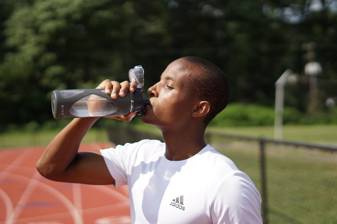 sports nutrition for young athletes - man in white crew neck t-shirt drinking from black sports bottle