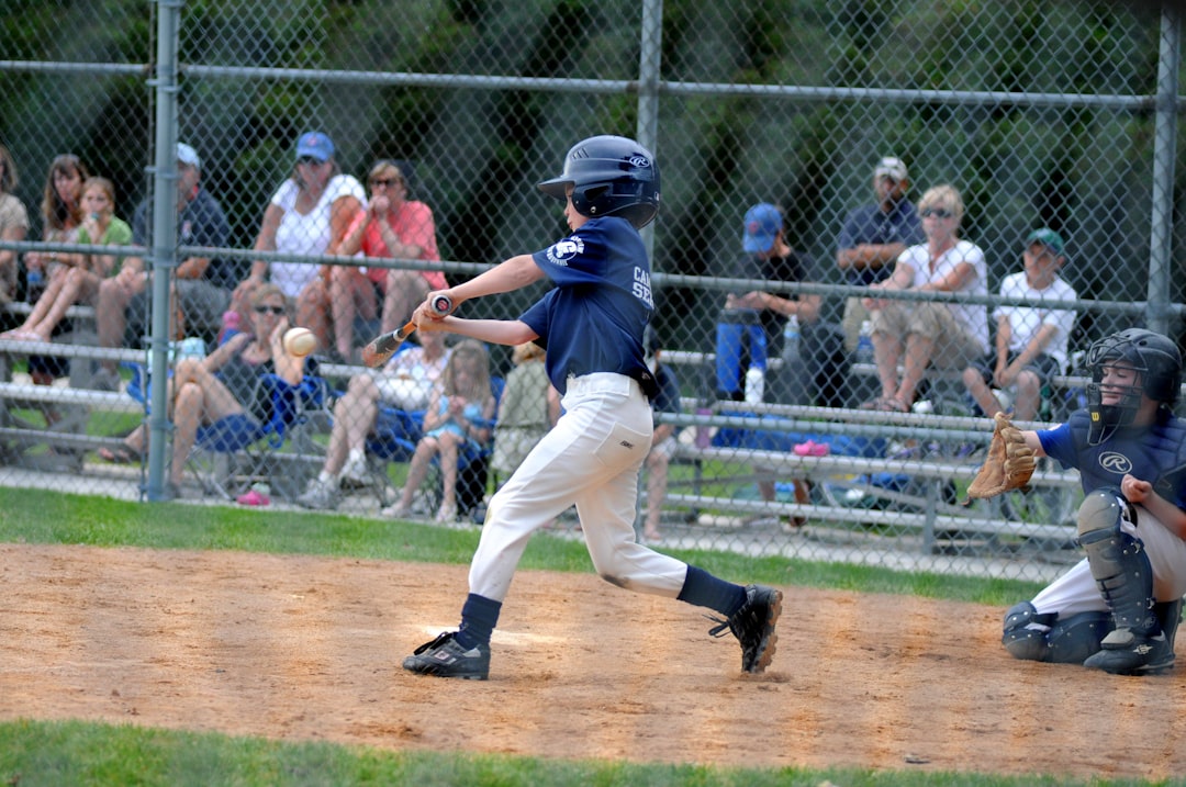 Youth Baseball Hitting Drills: 8 Proven Exercises to Improve Your Swing 1 youth baseball hitting drills - boy batting baseball near catcher beside gray fence