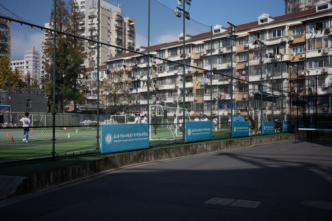 youth sports news April 2026 - People playing soccer on a field with apartments behind.