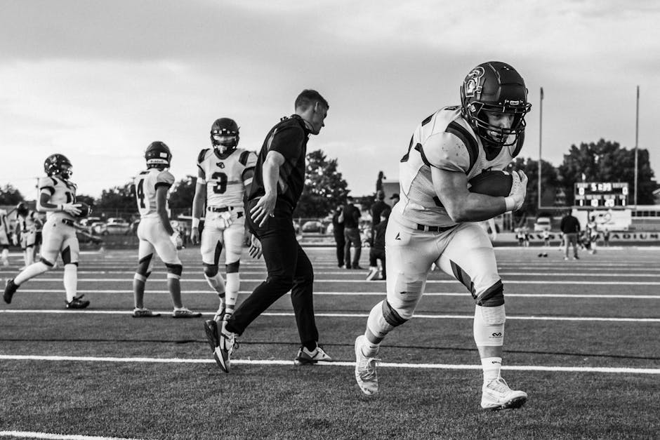 youth sports news April 2026 - High school football players practicing on the field in an intense black and white scene.