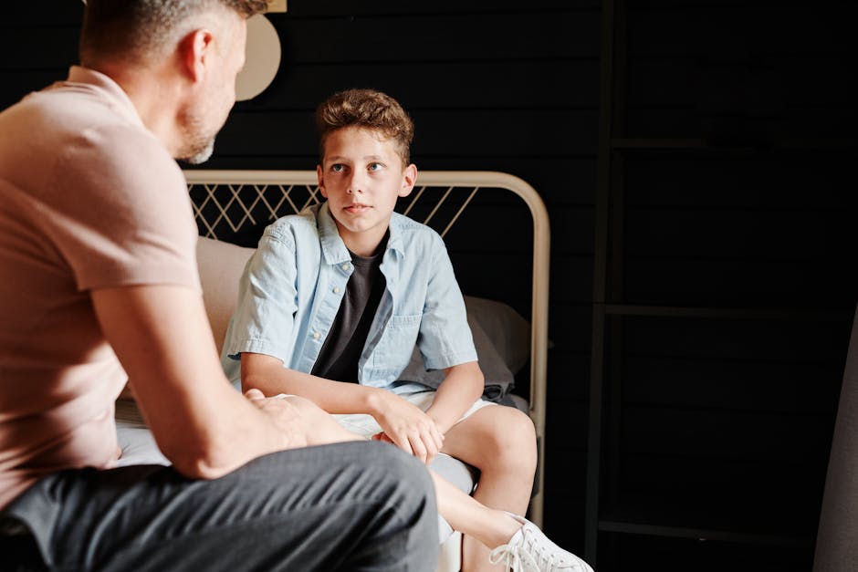 concussion symptoms parents should know - A father and son share a heartfelt conversation indoors, capturing a moment of bonding.