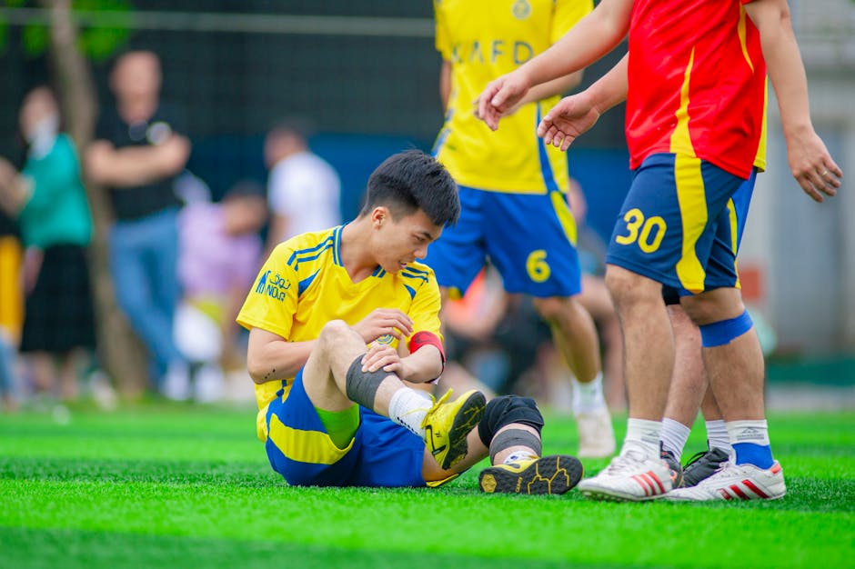 6 Crucial ACL Injury Prevention Exercises for Youth Athletes 1 Amateur soccer player sitting on grass, nursing a leg injury during game in Hanoi, Vietnam.