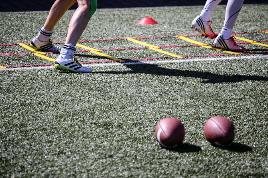 9 Essential Footwork Drills Every Young Athlete Needs to Build Athletic Foundation 1 Football players practice agility drills on a sunlit grass field with ladders and balls.
