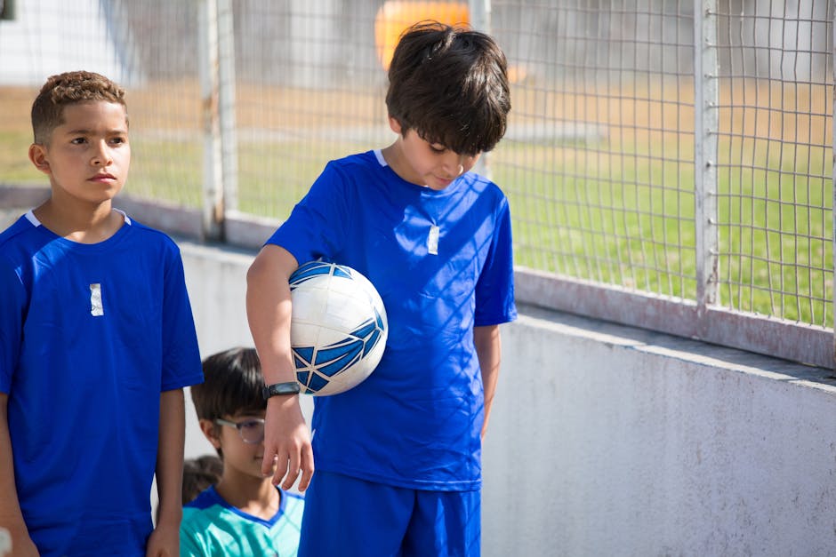 youth sports news May 2026 - A group of boys in blue uniforms preparing for a soccer game outdoors.