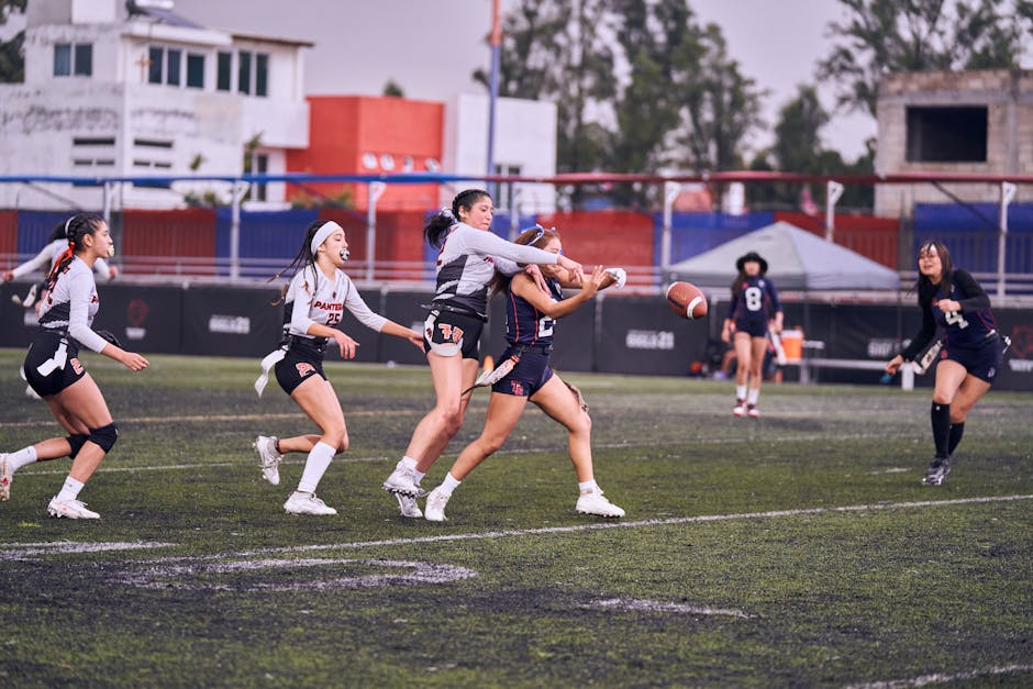 youth athlete development - Intense women's flag football game with players in motion on outdoor field.