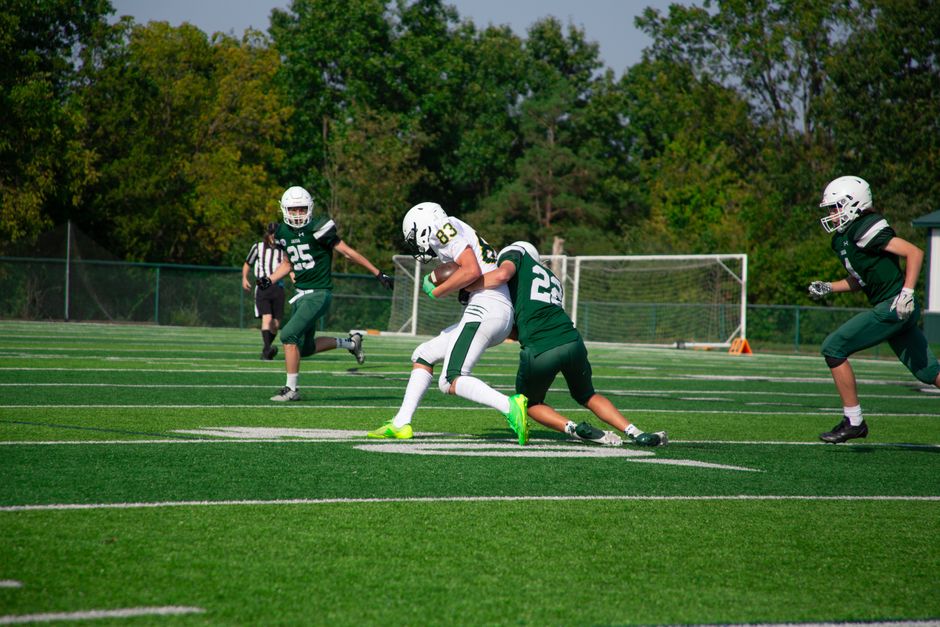 youth sports - Intense tackle during a high school football match on a sunny day.