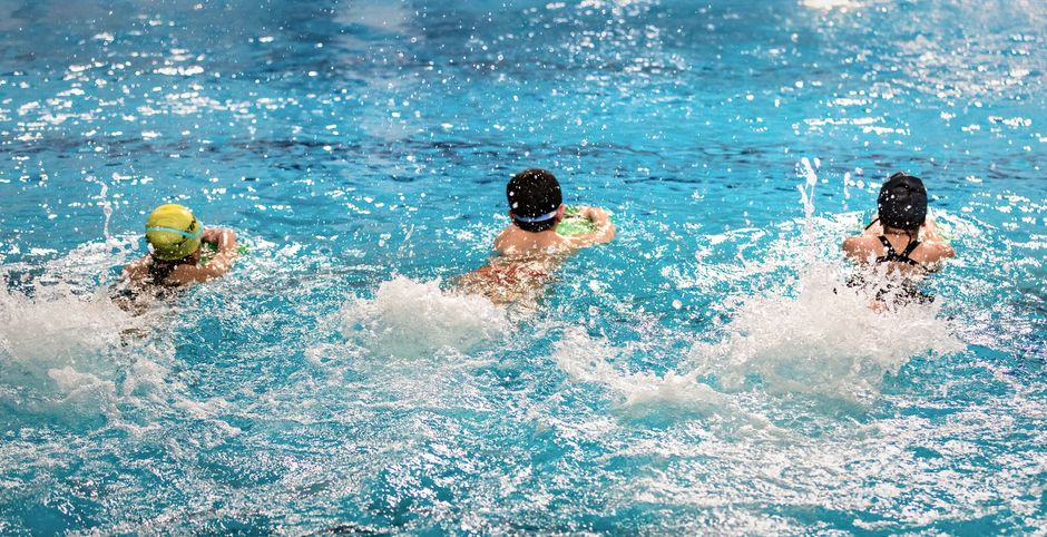 Jacksonville Girls' Sports Boom, Kansas Flag Football Debut, SafeSport Swim Coach Ban, AI Coaching Apps Surge: 15 Essential Youth Sports Stories (September 13, 2026) 1 youth sports - Three children swim freestyle in an indoor pool, splashing water, and having fun.