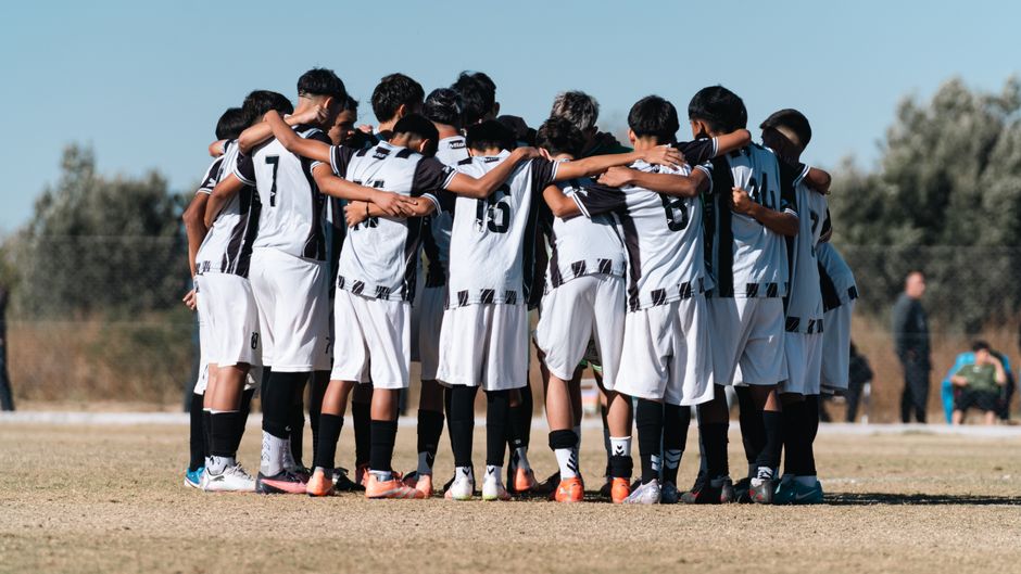 youth sports news - Youth soccer team huddling on the field, preparing for the game together.